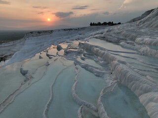 Pamukkale Travertines Cinematic Aerial Drone footage. Turkish famous white thermal bath with healthy clean water in a beautiful sunset. 