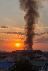 Uralsk, Kazakhstan, 27.08.2022 - Black smoke from the city's landfill fire rises high into the sky. Fire in the city at sunset. Burning landfill in the city of Uralsk.