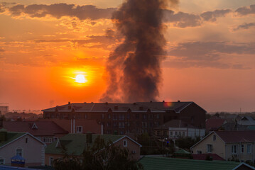 Uralsk, Kazakhstan, 27.08.2022 - Black smoke from the city's landfill fire rises high into the sky. Fire in the city at sunset. Burning landfill in the city of Uralsk.
