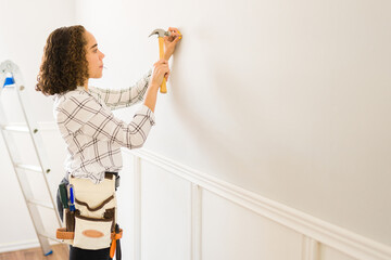 Handy woman hammering to put decorations in the wall