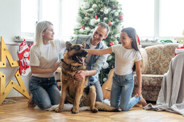 Merry Christmas and Happy New Year. Happy family with dog are waiting for the New Yearwhile sitting...