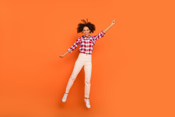 Full length body size view of attractive cheerful girl jumping holding copy space isolated on bright orange color background