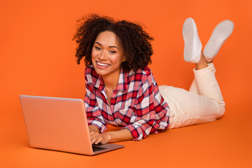 Portrait of attractive cheery girl lying using laptop ui web study education isolated on bright...
