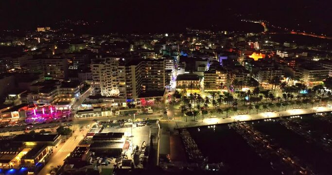 City lights at night, facing the marina. Aerial video of the skyline and the streets full of vehicles. Sant Antoni de portmany, Ibiza.