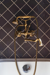 Golden faucet and shower in vintage style on a background of brown tiles. High quality photo