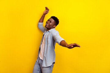Photo of optimistic young brunet guy dance wear jeans shirt isolated on yellow color background