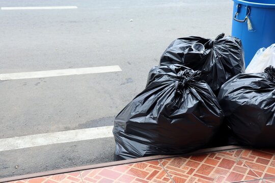 Garbage bags, black bin bags, on the foot path. Environment and object concept.