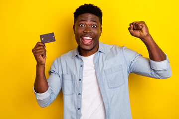 Photo of ecstatic guy hold credit card fist up celebrate income earnings isolated bright color background