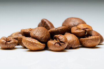 a heap of  rosted coffee beans on a white background with reflection