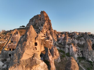 Aerial view of natural rock formations in the sunset, valley with cave houses in Cappadocia, Turkey. Natural landscape city lights at the night.