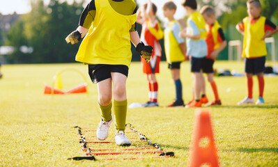 School Boy Running Slalom Track Between Training Poles and Jumping Over Ladders. Teenage Football...