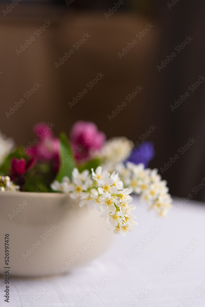 Sticker Spring blooming delicate flowers in a round vase on a table with a white tablecloth, a pastel bouquet and a delicate floral card	