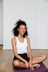 Black woman smiling and doing exercise during yoga practice