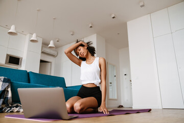 Black young woman using laptop during yoga practice