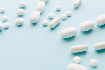 Scattered white pills on blue table. Mock up for special offers as advertising, web background or other ideas. Medical, pharmacy and healthcare concept. Copy space. Empty place for text or logo.
