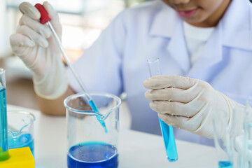 Asian boy use bulb to suck and drop liquid in glass tube