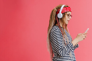 White woman with dreadlocks using cellphone while listening music