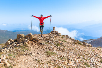 a female climber conquers the peak against the background of the blue sky enters the mountain with...