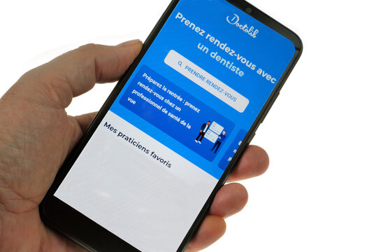 Vannes, France, 27 août 2022 : Application Doctolib sur un smartphone tenu en main en gros plan sur fond blanc