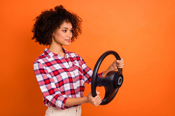 Photo of shiny sweet young lady dressed checkered shirt riding car looking empty space isolated orange color background