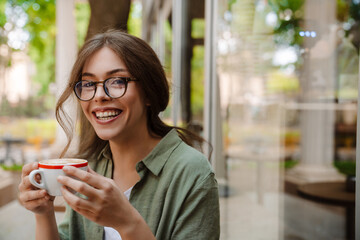 Portrait of young beautiful smiling woman in glasses with coffee