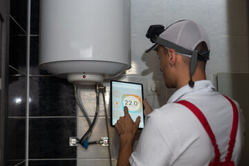 The technician checking the heating system in the boiler room with tablet in hand.