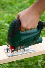 An electric jigsaw cuts the board in half.