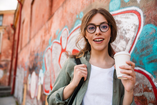 Young beautiful smiling woman in glasses with coffee looking camera