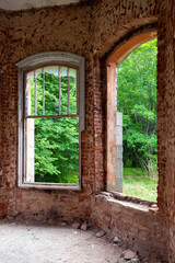Abandoned red brick building windows without glasses, view from inside of green trees