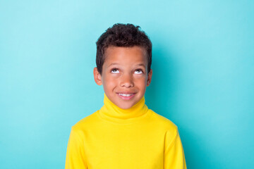 Portrait of positive creative boy toothy smile look interested up empty space isolated on emerald...
