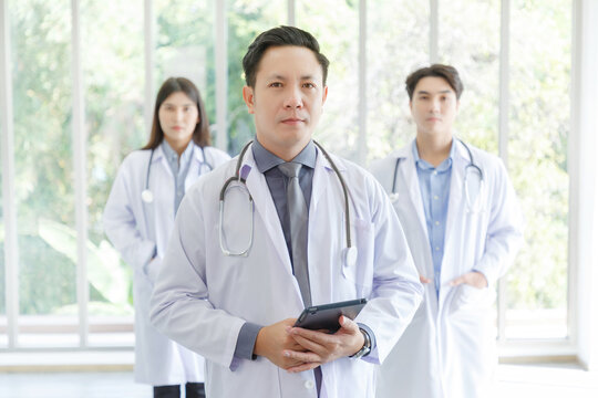 Medicine And Healthcare Concept : Group Of Serious Asian Doctors Line Up, Male And Female Are Standing In Lobby Of Hospital.