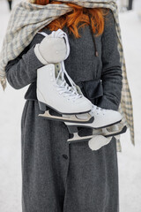 woman is resting and walking in the park in winter, a happy European woman with red hair is skating. a young and beautiful woman in a gray vintage coat is enjoying the Christmas holidays