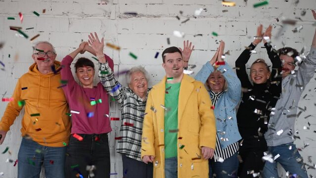 Diverse group of cheerful people standing together and celebrating with confetti