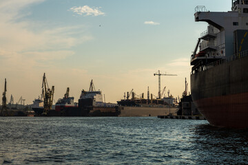 przemysłowa część portu w Gdańsku z licznymi okrętami i dźwigami - obrazy, fototapety, plakaty