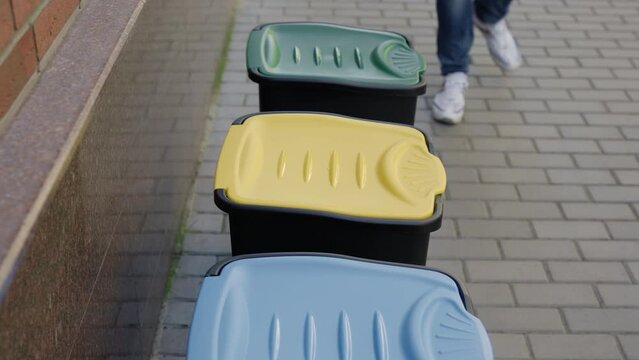 Close view of the sorting bin and the male hands in gloves puts plastic bottle inside the sorting bin. Volunteer is sorting the plastic bottles into the bins