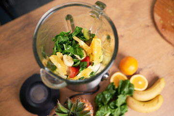 Still life overhead shot of chopped fruit and spinach in glass blender smoothie