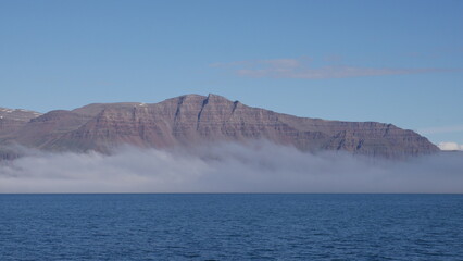 Mountain in fog in Greenlandic fjord