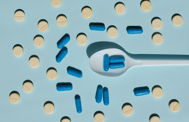 Multi-colored capsules lie on the table. Spoon with pills. Medicine for illness. Vitamins and biologically active additives. Medicine and healthcare.