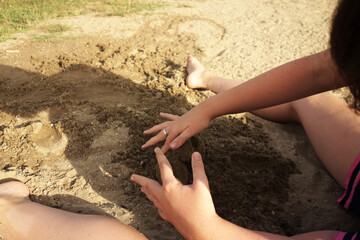 child hands and feet in the sand makes among us