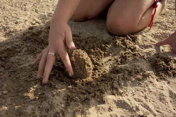child hands and feet in the sand makes among us