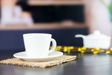 international coffee day, traditional colombian drink, close-up of coffee mug on the black kitchen table decorated with flowers in the background