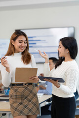 A picture of two Asian business women discussing at a meeting.