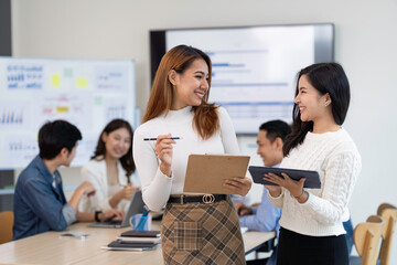 A picture of two Asian business women discussing at a meeting.