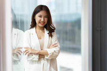 Charming Smiling Asian businesswoman a smile standing and looking at the camera over office background