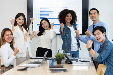 business team celebrates corporate victory together in the office, happy overjoyed professionals group rejoices company victory, teamwork success win triumph concept at the conference table
