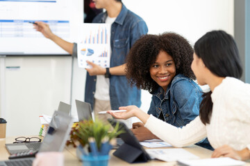 Fototapeta premium A happy Afro-American and multi-ethnic business men and women working together online on laptops in company offices.