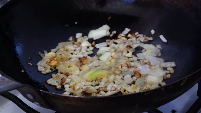 brunoise onion frying on a pan