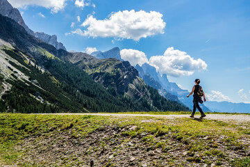 Fototapeta premium Girl walking down a mountain path. San Martino di Castrozza, Trentino Alto Adige - Italy