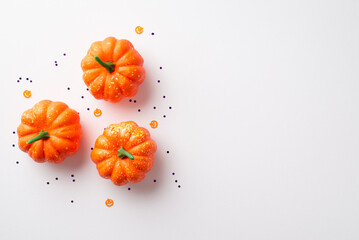 Halloween concept. Top view photo of orange pumpkins and confetti on isolated white background with...