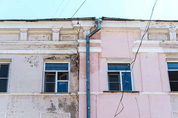 Fragment of a historic building with cracks and a shabby facade. Poor repair and painting of the...